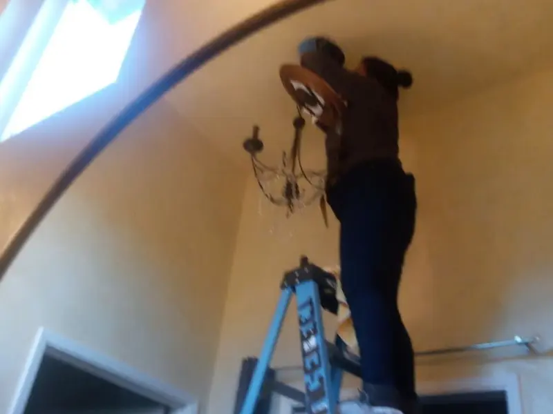 Electrician installing a chandelier in a Marshall residence